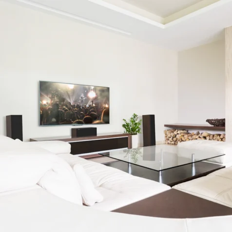 RP-500C-II-sitting-on-a-credenza-under-a-TV-with-grille-on-in-front-of-a-large-glass-coffee-table